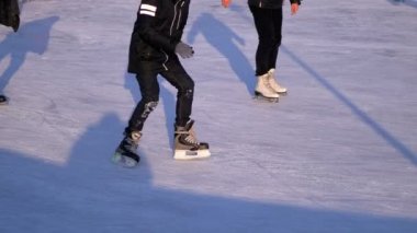 İnsan kalabalığı güneşli bir günde patinaj buz pateni pisti üzerinde vardır. Ağır çekim. Birçok kişi paten buz pateni kış açık.