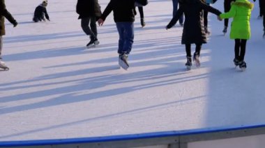 İnsan kalabalığı güneşli bir günde patinaj buz pateni pisti üzerinde vardır. Ağır çekim