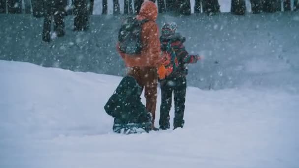 Familie van vader, moeder, zoontje en dochter rijden op een slee in een dennenbos in sneeuwval. Slow Motion — Stockvideo