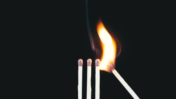 Trois allumettes allument une flamme sur un fond noir, puis sort créant beaucoup de fumée — Video