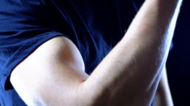 Pazı bir genç adamın elinde siyah bir tişört ve siyah arka plan üzerinde yukarı pompalanır