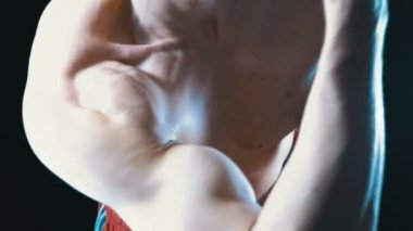 Kaslı erkek atlet kırmızı seksi vücut esneme kol kasları siyah bir arka plan üzerinde şort