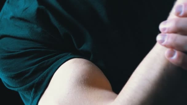 Aufgepumpter Bizeps auf der Hand eines jungen Mannes auf schwarzem Hintergrund und in einem schwarzen T-Shirt — Stockvideo