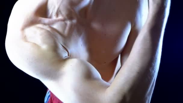 Сексуальное тело мускулистого спортсмена в красных шортах, демонстрирующего мышцы рук на черном фоне — стоковое видео