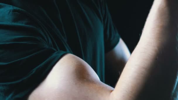 Opgepompt Biceps op een jonge Mans Hand op zwarte achtergrond en in een zwart T-shirt — Stockvideo