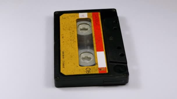 Vintage gelbe Audiokassette dreht sich auf weißem Hintergrund — Stockvideo