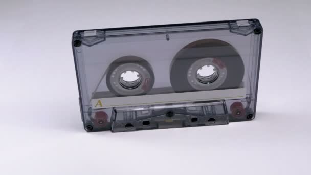 Винтажная прозрачная аудиокассета вращается на белом фоне — стоковое видео