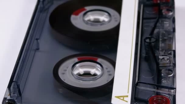 Винтажная прозрачная аудиокассета вращается на белом фоне — стоковое видео