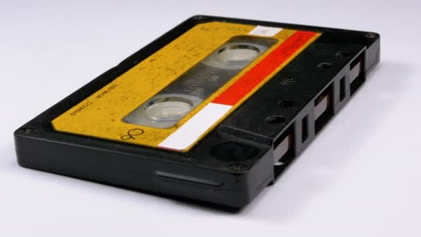 Vintage gelbe Audiokassette dreht sich auf weißem Hintergrund — Stockvideo