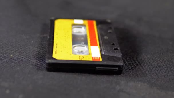 Casete de audio amarillo vintage gira sobre fondo negro — Vídeo de stock