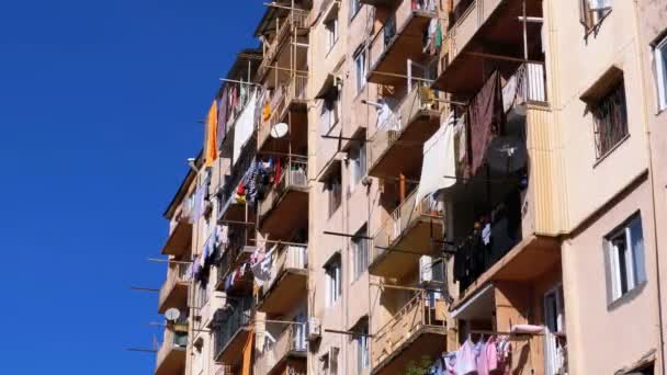 Сушка одежды на бельевой верёвке между балконами высотного старого дома в бедной части города — стоковое видео