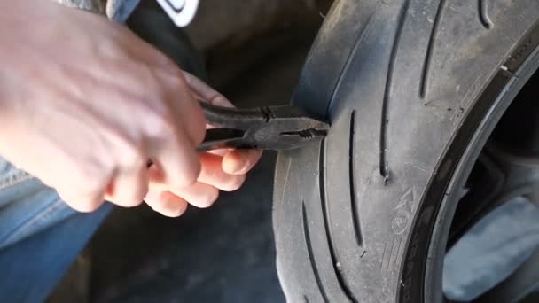 Estrarre il chiodo dal pneumatico della ruota del motociclo utilizzando pinze — Video Stock