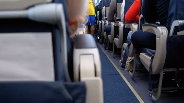 Пассажиры в салоне пассажирских самолетов, сидящие на стульях во время полета — стоковое видео