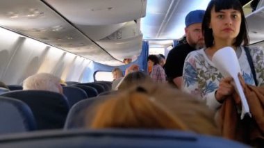 Yatılı. Kabindeki uçağın koltukları arasında yer alan şeylerle uçağın yolcuları koltuklarına geçerler..