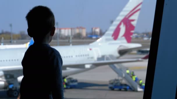 Silhouette di un bambino e padre davanti alla finestra terminale guardando gli aerei — Video Stock