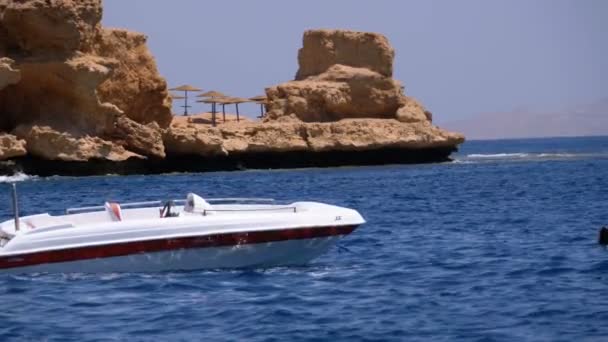 Barco a motor en el ancla en el mar contra el paisaje de la playa rocosa y la costa en Egipto — Vídeos de Stock