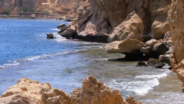 Rocky Beach en Egipto. Playa en una bahía en la costa con olas en el mar azul y arrecifes de coral. Moción lenta — Vídeo de stock