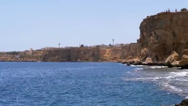 Rocky Beach, no Egipto. Praia em uma baía na costa com ondas no mar azul e recifes de coral — Vídeo de Stock