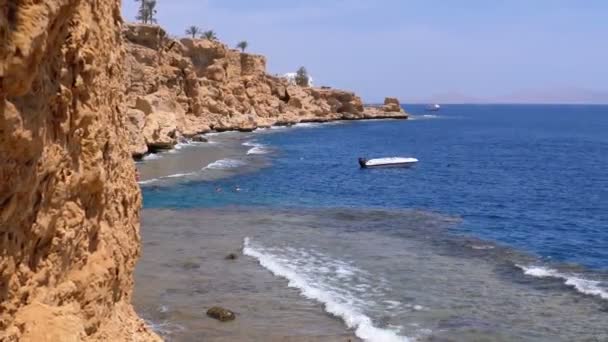 Rocky Beach, no Egipto. Praia em uma baía na costa com ondas no mar azul e recifes de coral — Vídeo de Stock