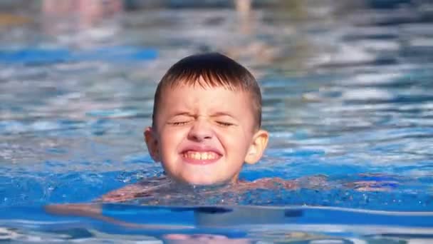 Niño feliz nada en una piscina con agua azul. Moción lenta — Vídeos de Stock