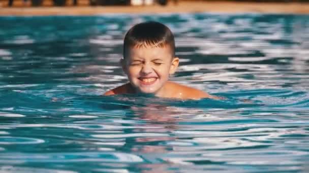 Happy Boy nada em uma piscina com água azul. Movimento lento — Vídeo de Stock