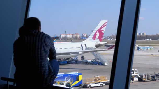 Silueta de un niño y padre delante de la ventana terminal mirando a los aviones — Vídeos de Stock