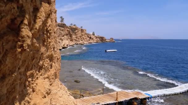 Rocky Beach v Egyptě. Pláž v zálivu na pobřeží s vlnami v modrém moři a korálových útesech — Stock video