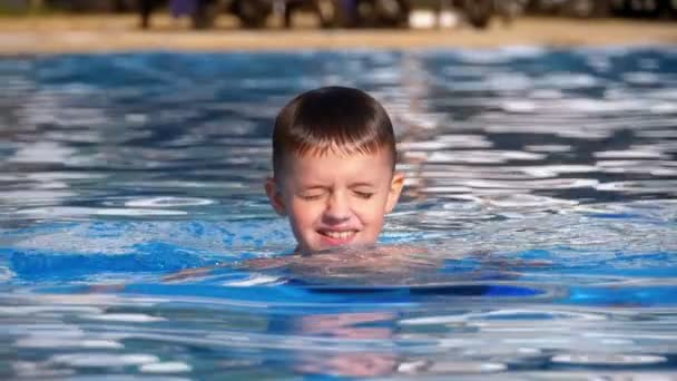 Happy Boy swims a medencében kék víz. Lassított mozgás — Stock videók