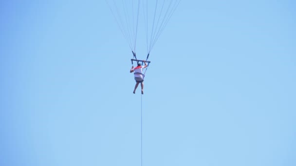 Человек на веревке пролетает над красным морем на парашюте над лодкой — стоковое видео
