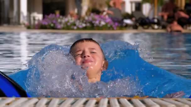 Счастливый мальчик с колясками плавает в бассейне с голубой водой. Slow Motion — стоковое видео