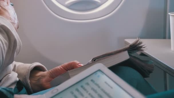 Passagiers lezen en oplossen van een kruiswoordpuzzel tijdens de vlucht — Stockvideo