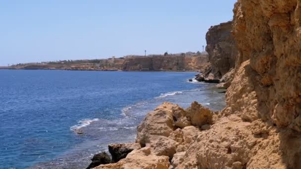 Rocky Beach en Egipto. Playa en una bahía en la costa con olas en el mar azul y arrecifes de coral. Moción lenta — Vídeos de Stock