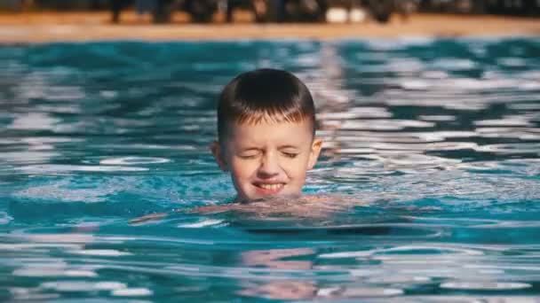 Niño feliz nada en una piscina con agua azul. Moción lenta — Vídeos de Stock