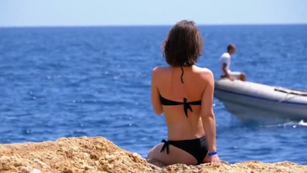 Сексуальна дівчина в купальнику з екзотичним коктейлем сидить на пляжі проти Червоного моря в Єгипті — стокове відео