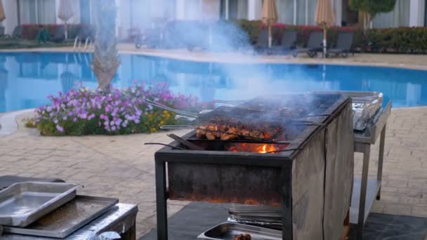 Hühnergrill wird auf einem großen Grill von einem Koch im Hotel am Pool mit blauem Wasser gekocht. Ägypten — Stockvideo