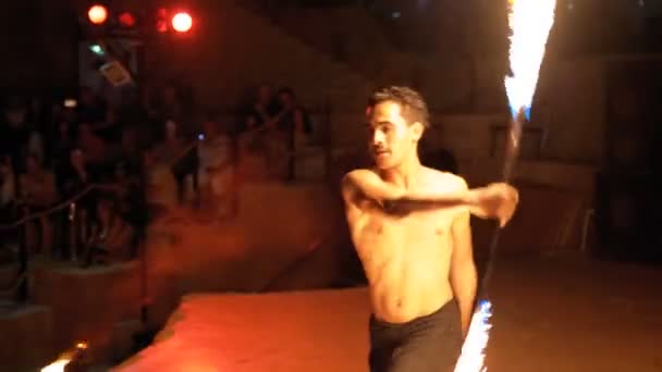 Feuershow auf der Bühne. junger Mann tanzt mit feurigen Fans in einer Nachtshow. Zeitlupe — Stockvideo