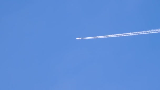 Avión de pasajeros vuela en el cielo despejado dejando atrás un rastro de humo — Vídeos de Stock