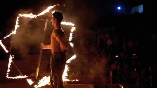 Feuershow auf der Bühne. junger Mann tanzt mit feurigen Fans in einer Nachtshow. Zeitlupe — Stockvideo