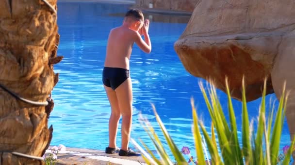 Niño feliz con aletas saltando a la piscina de agua azul. Moción lenta — Vídeo de stock