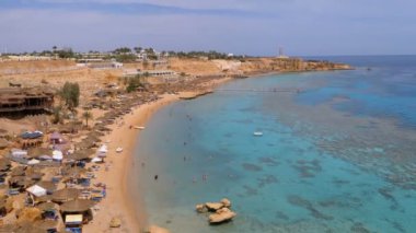 Reef'teki Luxury Sea Hotel'de Şemsiye, Şezlong ve Palmiyelerle Mercan Plajı'nın panoramik manzarası. Mısır.
