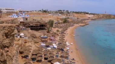 Reef'teki Luxury Sea Hotel'de Şemsiye, Şezlong ve Palmiyelerle Mercan Plajı'nın panoramik manzarası. Mısır.