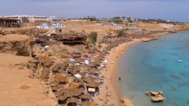 Reef'teki Luxury Sea Hotel'de Şemsiye, Şezlong ve Palmiyelerle Mercan Plajı'nın panoramik manzarası. Mısır.