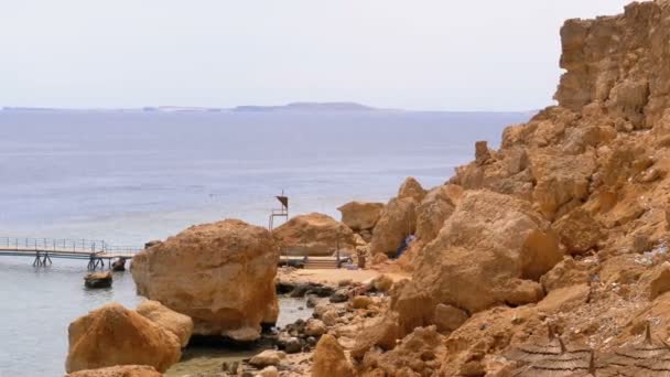 Playa rocosa con paraguas cerca de Acantilado en el Mar Rojo en Coral Reef. Egipto . — Vídeo de stock