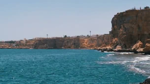 Rocky Beach en Egipto. Playa en una bahía en la costa con olas en el mar azul y arrecifes de coral — Vídeos de Stock