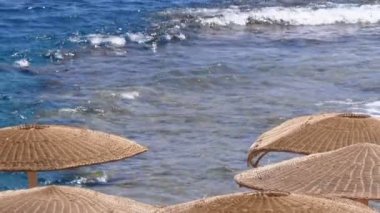 Mısır 'da şemsiyeli boş plaj Kızıl Deniz' deki mercan resifinin arka planında