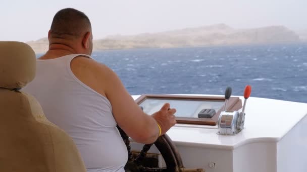 Fat Captain bestuurt het toeristische jacht in Sea Storm. Stuurwiel van een plezierboot. — Stockvideo