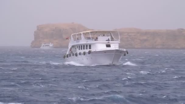 Plezierboot met toeristen zeilen in de stormachtige zee op de achtergrond van rotsen. Egypte — Stockvideo