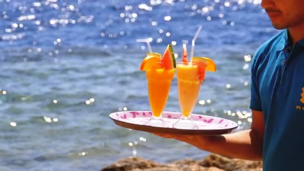 Экзотические коктейли в стакане с соломой на подносе на фоне моря. Египет . — стоковое видео