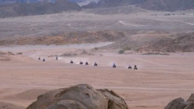 Dağların arka planında Mısır'da Çöl üzerinden bir Quad Bike Rides Sütun. Sürüş Avs.