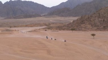 Dağların arka planında Mısır'da Çöl üzerinden bir Quad Bike Rides Sütun. Sürüş Avs.